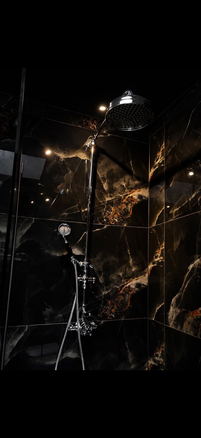Luxury rainfall shower running in black tiled enclosure